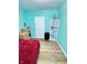 Bedroom with wood floors, turquoise walls, shelves, and a comfy red bed at 424 S Parker Ave, Indianapolis, IN 46201