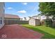 A backyard featuring a patio, green lawn, wooden fence, storage shed, and some flowers at 4316 Village Trace Dr, Indianapolis, IN 46254