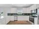 Modern kitchen featuring stainless steel appliances, white cabinets, and green backsplash at 4763 W Tradwell Dr, New Palestine, IN 46163