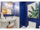Stylish bathroom featuring a floating sink, modern gold fixtures, subway tile, and a striking navy blue accent wall at 5034 N Capitol Ave, Indianapolis, IN 46208