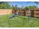 Backyard view of a swing set and slide on the grassy lawn, bordered by a wooden fence at 540 Hanley St, Plainfield, IN 46168