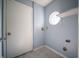 A basic laundry room with light blue walls, tile flooring, and a round window at 5622 Mead Ct, Indianapolis, IN 46220