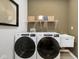 Functional laundry room with modern washer and dryer units, storage shelves, and utility sink at 583 Dalton Way, Avon, IN 46123