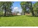 Lush backyard features a green lawn, mature trees, detached garage, and plenty of open space at 633 Park Dr, Greenwood, IN 46143