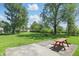 Expansive backyard featuring lush lawn, mature trees, and a red picnic table on a concrete patio at 633 Park Dr, Greenwood, IN 46143