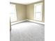 A sunny bedroom with neutral walls, plush gray carpeting, and two windows providing natural light and street views at 660 N 700 E, Whitestown, IN 46075