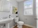 Stylish powder room featuring a pedestal sink, modern faucet, and natural light from the window at 6665 Boxcar Pl, Indianapolis, IN 46220