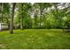 Large grassy backyard surrounded by mature trees and a fence at 7531 Mohawk Ln, Indianapolis, IN 46260