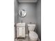Compact bathroom featuring a modern sink and toilet with gray walls and a round mirror at 7531 Mohawk Ln, Indianapolis, IN 46260