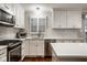 Well-lit kitchen with stainless steel appliances, white cabinetry, and hardwood floors at 7531 Mohawk Ln, Indianapolis, IN 46260