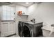 Functional laundry room with modern washer and dryer, shelving, and convenient utility sink at 7531 Mohawk Ln, Indianapolis, IN 46260