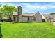 Grassy backyard view of the home with stone chimney at 9255 Fireside Dr, Indianapolis, IN 46250