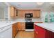 Charming kitchen featuring a central island, warm wood cabinetry, and black appliances at 10833 Tournament Ln, Indianapolis, IN 46229