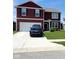 Two-story red house featuring an attached garage, well-maintained lawn, and a long driveway at 11204 Sashing Way, Monrovia, IN 46157