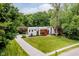 Aerial view of a modern home with long driveway, large lawn, and wooded backdrop at 11911 Eden Glen Dr, Carmel, IN 46033