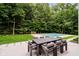 Beautiful backyard with a patio dining set and an inground pool surrounded by mature trees at 11911 Eden Glen Dr, Carmel, IN 46033
