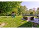 A lush backyard features a playset, mature trees, and a furnished patio area at 1238 Aggie Ln, Indianapolis, IN 46260