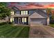 Two-story home featuring a brick facade, attached two-car garage, and a well-manicured front lawn under a dramatic sunset sky at 1238 Aggie Ln, Indianapolis, IN 46260