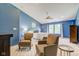 Inviting main bedroom boasts blue walls, ceiling fan, sitting area with chairs, and bright windows at 1238 Aggie Ln, Indianapolis, IN 46260