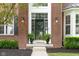 Inviting front entrance features decorative ferns flanking the doorway and classic brickwork with stylish lighting at 13234 Amundson Dr, Carmel, IN 46074