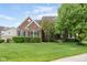 Classic brick home featuring lush green lawn, tidy hedges, and a grand mature tree creating a welcoming view at 13234 Amundson Dr, Carmel, IN 46074