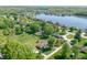 An aerial view features several homes near a lake surrounded by mature trees and green lawns at 1328 Toner Dr, Anderson, IN 46012