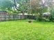 Spacious backyard features green grass, a fire pit, mature trees, and a wooden fence for privacy at 310 S Butler Ave, Indianapolis, IN 46219