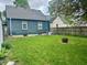 View of a spacious backyard with a fire pit and green grass, surrounded by a wooden fence at 310 S Butler Ave, Indianapolis, IN 46219