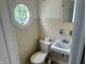 Cozy bathroom featuring white tile, toilet, small sink and an octagon shaped window with natural light at 310 S Butler Ave, Indianapolis, IN 46219