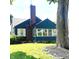 Quaint home with brick chimney, white-trimmed windows, and a lush green lawn accentuated by a large tree at 310 S Butler Ave, Indianapolis, IN 46219