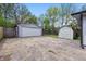 Detached garage and shed located in backyard with an expansive concrete driveway and surrounded by greenery at 316 S Roena St, Indianapolis, IN 46241