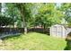Spacious backyard with mature trees, a fire pit area with chairs, and a convenient storage shed at 3608 Valley Lake Dr, Indianapolis, IN 46227