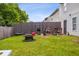 View of the grassy backyard with tall wooden privacy fence, fire pit, grill and yard equipment at 3937 Candle Berry Dr, Indianapolis, IN 46235