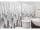 Bathroom with vanity, sink, and toilet with white and gray forest-themed shower curtain at 3937 Candle Berry Dr, Indianapolis, IN 46235