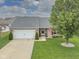 Charming brick home featuring a two-car garage, a well-manicured lawn, and mature trees at 4309 Viva Ln, Indianapolis, IN 46239
