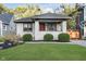 Classic white brick home with vibrant red door, neatly landscaped lawn, and inviting front porch, exuding warmth at 6167 Carrollton Ave, Indianapolis, IN 46220