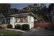 Quaint white brick home with a red door, complemented by lush greenery and a driveway, offering curb appeal at 6167 Carrollton Ave, Indianapolis, IN 46220