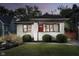 Charming white brick home featuring a bright red front door, a covered porch, and beautifully manicured landscaping at 6167 Carrollton Ave, Indianapolis, IN 46220