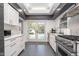 Modern kitchen with white cabinets, stainless steel appliances, marble countertops, and a view of the backyard pool at 6167 Carrollton Ave, Indianapolis, IN 46220