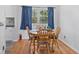 Bright dining area featuring hardwood floors, wooden table, and blue patterned curtains at 6191 Geneva St, Stilesville, IN 46180