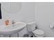 Clean half bathroom with a pedestal sink, round mirror, and white toilet at 6903 Aster Dr, Pendleton, IN 46064