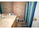Bathroom with a marble counter, wood cabinets, and blue striped shower curtain at 6913 Thousand Oaks Ln, Indianapolis, IN 46214