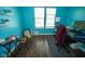 Bedroom featuring light blue walls, laminate flooring, two windows, and a comfortable chair and desk setup at 6913 Thousand Oaks Ln, Indianapolis, IN 46214