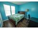 Cozy bedroom featuring two windows offering natural light, complemented by laminate floors and a calming blue wall at 6913 Thousand Oaks Ln, Indianapolis, IN 46214