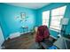 Bedroom featuring light blue walls, laminate flooring, two windows, and a comfortable chair and desk setup at 6913 Thousand Oaks Ln, Indianapolis, IN 46214
