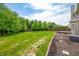 Large grass backyard with a wooden fence, mulch beds, mature trees, and a wooden deck at 7023 Hartington Pl, Indianapolis, IN 46259