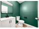 A sleek half-bathroom with modern vanity, stylish fixtures, and green accent wall at 7023 Hartington Pl, Indianapolis, IN 46259