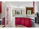 Bright kitchen with red cabinets, modern appliances, and a view to a window-filled living space at 7023 Hartington Pl, Indianapolis, IN 46259