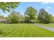 Well-manicured front yard with lush green lawn, mature trees, and a winding driveway leading to a charming single-story home at 7189 Creekwood Estates, Brownsburg, IN 46112