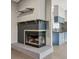 Fireplace with tile surround, custom shelves, next to a kitchen with blue cabinets and granite countertops at 7645 Madden Dr, Fishers, IN 46038